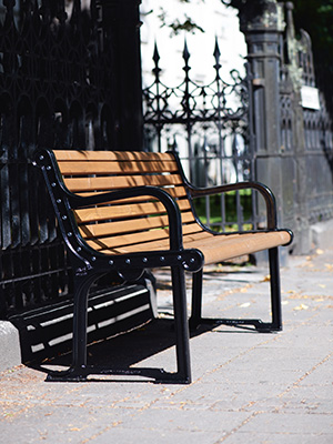 A wooden park bench with black steel legs and armrests.